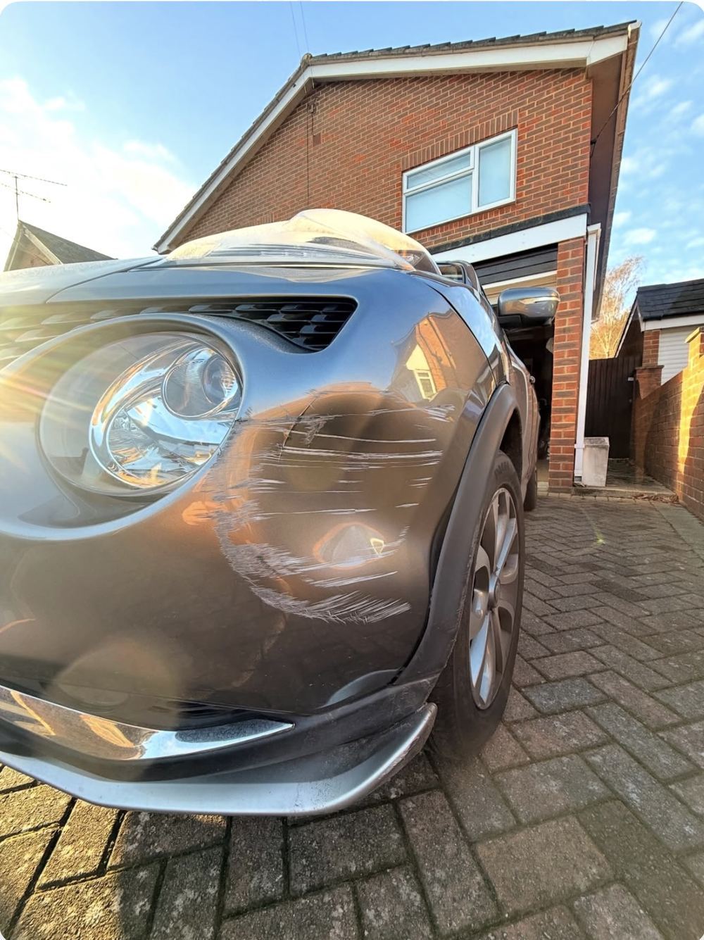 Nissan Juke front bumper with deep scrape and dent before repair